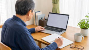 ノートを見ながらパソコンでブログ操作を覚える60代男性