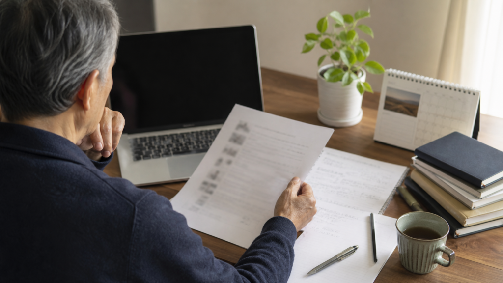 60代男性が自宅の机でブログ記事のメモを見返しながら反省点を整理する様子
